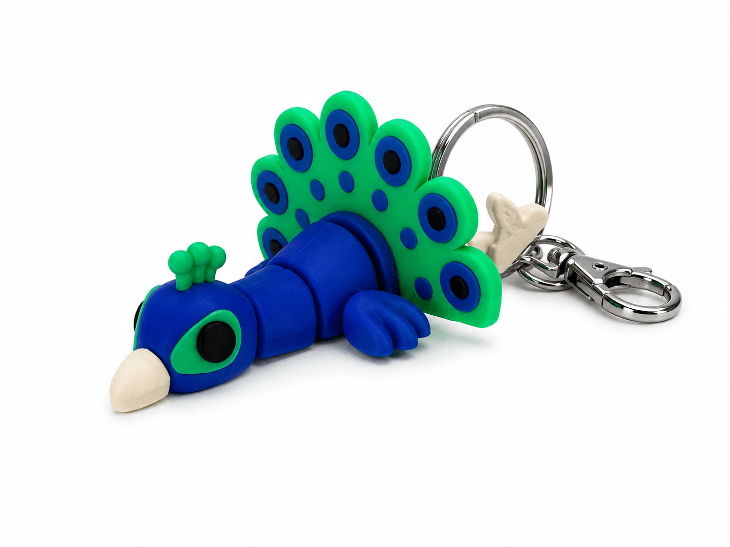 Blue and green clay peacock keyring lying on its side with a silver keyring attachment. Blue and green clay peacock keyring lying on its side with a silver keyring attachment.