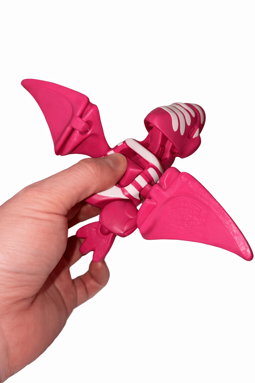 ChatGPT Image Mar 6 2026 02_53_46 PM AUTO-DRAFT: Pink toy dinosaur skeleton with wings, held in hand.